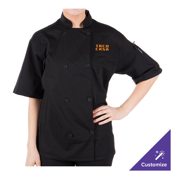 A woman wearing a Mercer Culinary black chef coat with a mesh back.