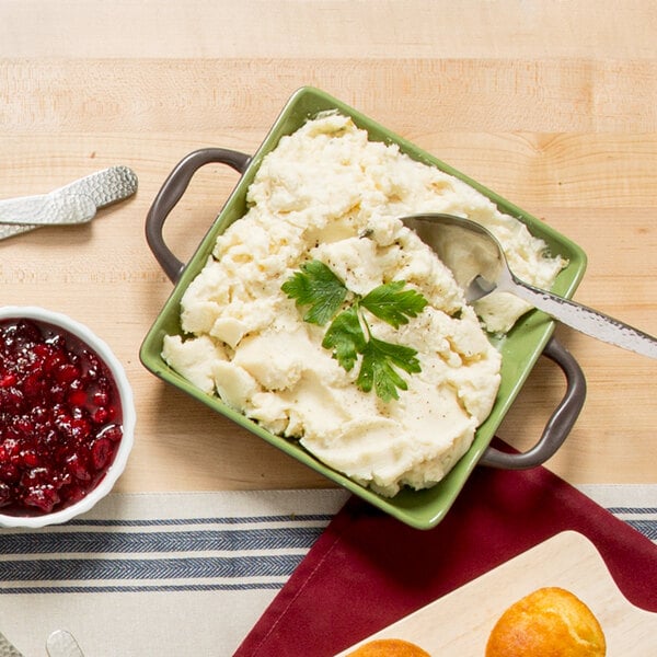 A Libbey stoneware square baker filled with mashed potatoes with a spoon in it.