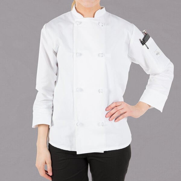 A woman wearing a white Mercer Culinary long sleeve chef jacket with cloth knot buttons.