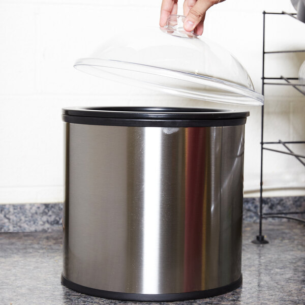 A hand holding a Carlisle lid over a silver Carlisle cold crock.