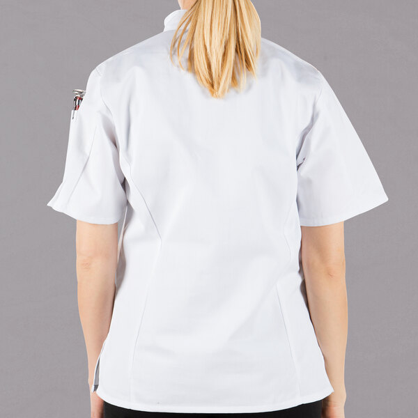 A woman wearing a Mercer Culinary white chef jacket with cloth knot buttons.