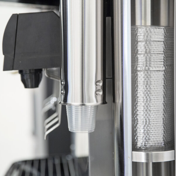 A close-up of a Vollrath stainless steel cup dispenser on a wall.