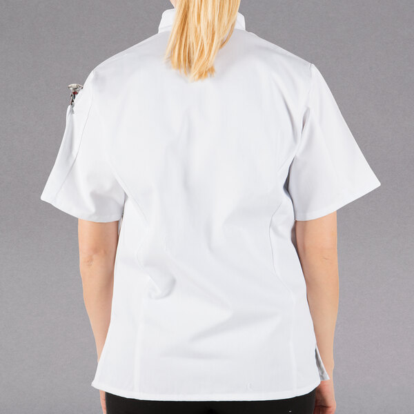 A woman wearing a white Mercer Culinary short sleeve chef jacket.
