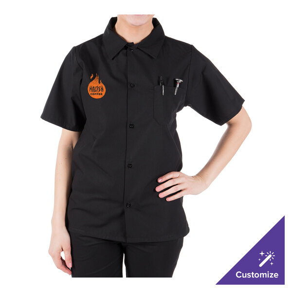 A person wearing a Mercer Culinary black cook shirt with a logo on the counter in a professional kitchen.