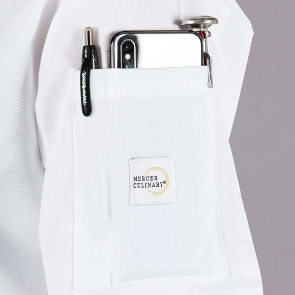 A white Mercer Culinary Millennia women's cook jacket with a pocket and pen.