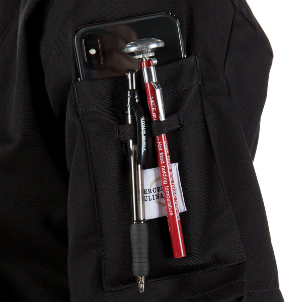A Mercer Culinary Millennia women's black chef coat with a phone and tools in the pocket.