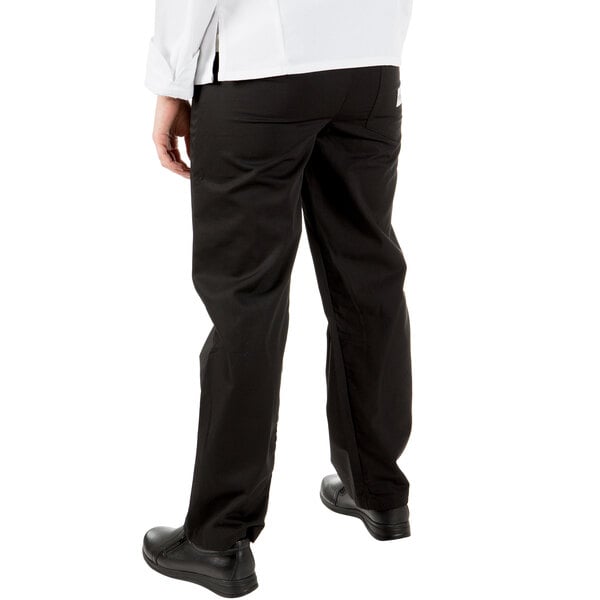 The lower body of a person wearing Mercer Culinary Millennia women's black chef pants.
