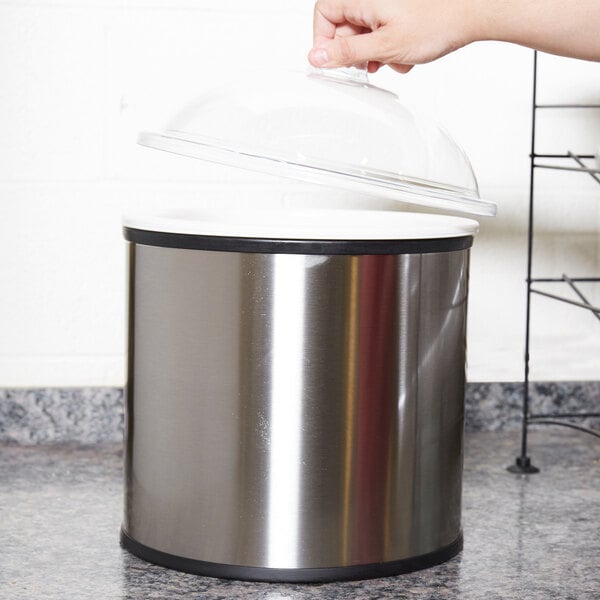 A person opening a lid on a stainless steel Carlisle Coldmaster crock.