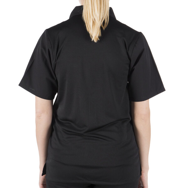 A woman wearing a Mercer Culinary Millennia black cook shirt with a mesh back.