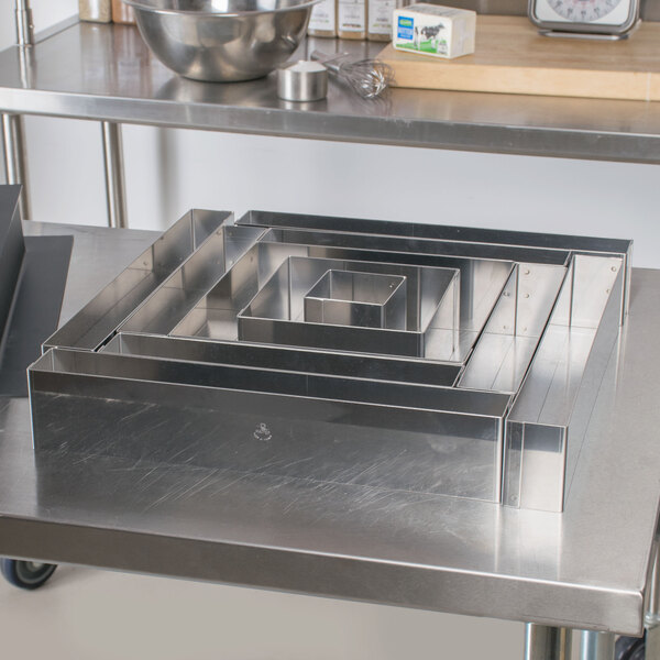 A Matfer Bourgeat stainless steel square wedding cake frame on a table.