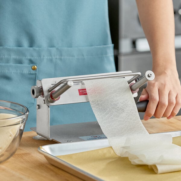 A stainless steel vegetable lasagna slicer being used to create thin sheets of vegetables.