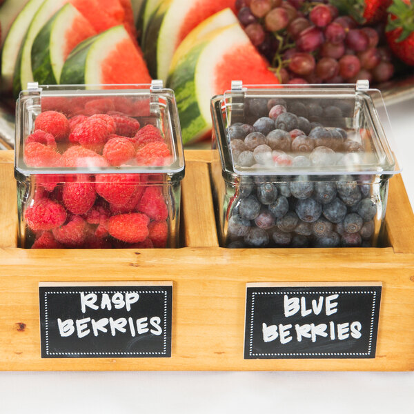 A wooden container with a Cal-Mil solid plastic lid holding raspberries and other berries.