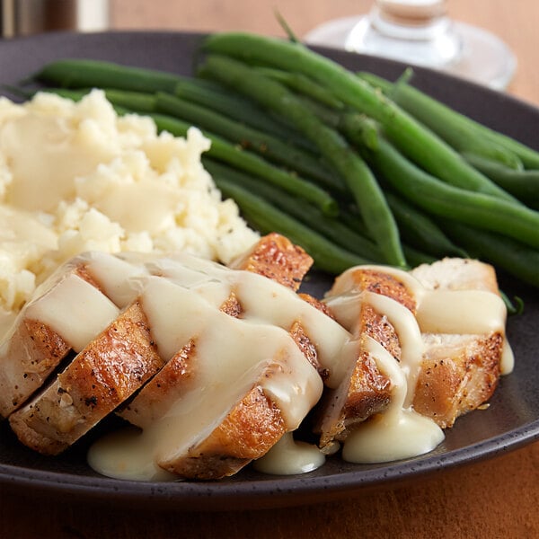 A plate of food with mashed potatoes, green beans, and Vanee Roasted Chicken Gravy.