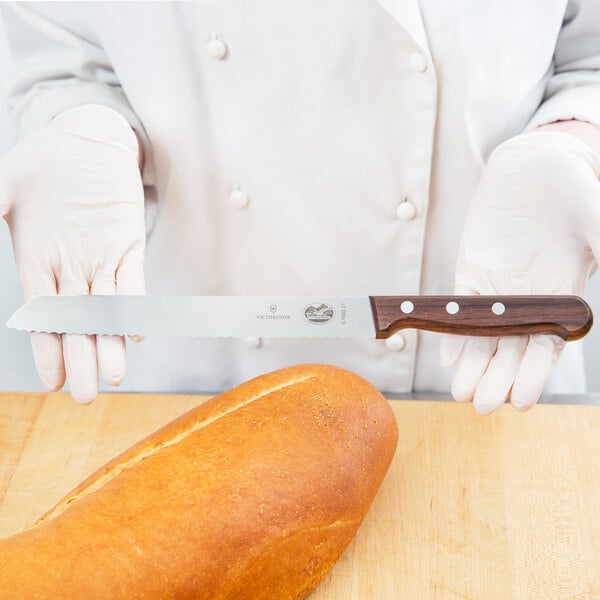 A person using a Victorinox bread knife to slice a loaf of bread.