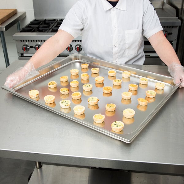 A person holding a Vollrath stainless steel steam table pan of food.