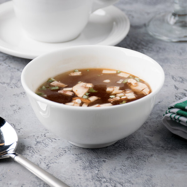 A bowl of soup with a spoon in a white bone china bowl.