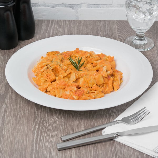 A Reserve by Libbey bone china round pasta bowl filled with pasta and a sprig of rosemary on a white background.