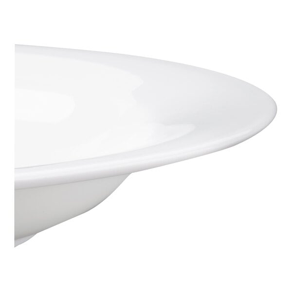 A partial view of a white, round, shallow bowl with a smooth, glossy finish.