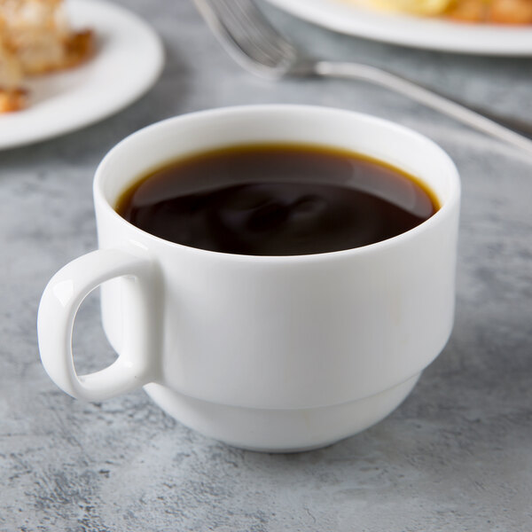 A Reserve by Libbey bone china cup of coffee with a spoon on a table.