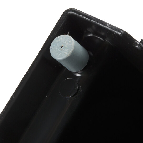 A close-up of a black plastic cylinder with a blue button.