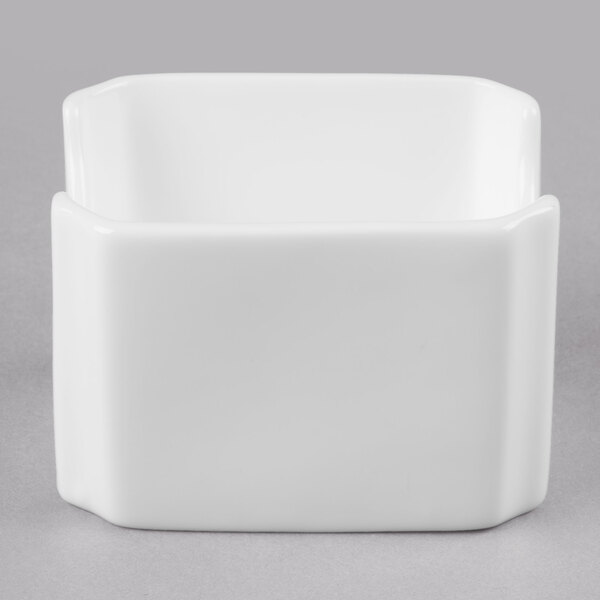 A white square bone china sugar packet holder with a lid on a gray surface.