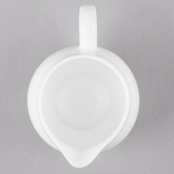 A white pitcher with a handle on a gray background.