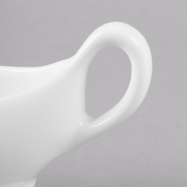 A close-up of a white Reserve by Libbey sauce boat with a handle.