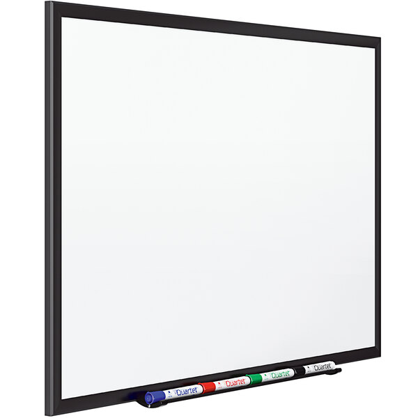 A white Quartet dry erase board with markers on it.