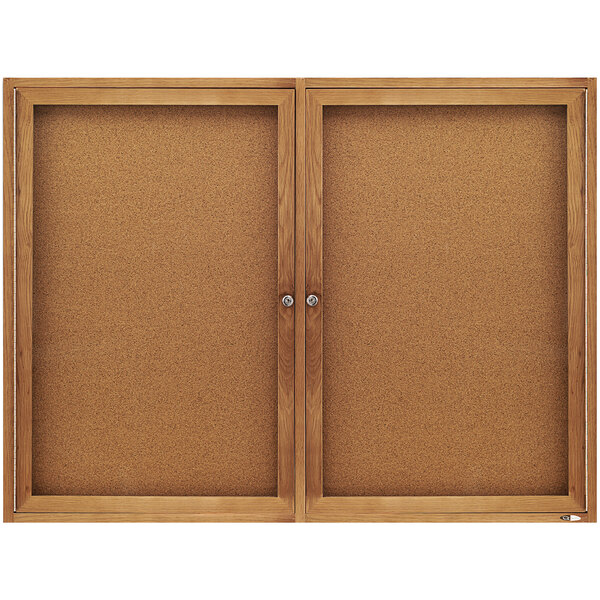 A Quartet enclosed cork board with oak frame and glass doors.