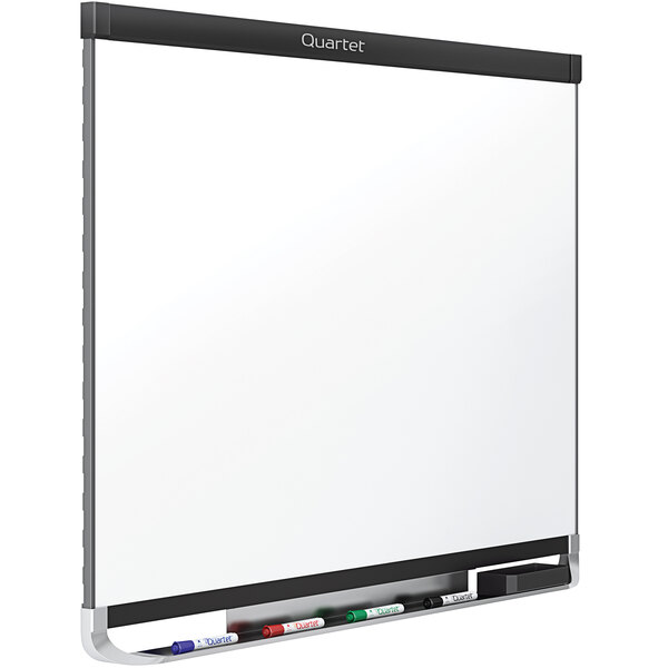 A Quartet Prestige magnetic porcelain dry erase board with a black frame and markers on it.