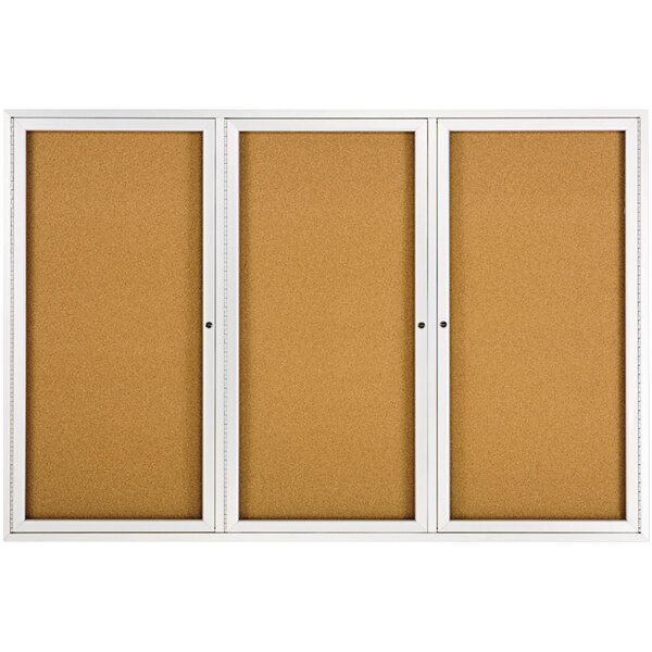 A white Quartet enclosed cork bulletin board with silver aluminum frame.