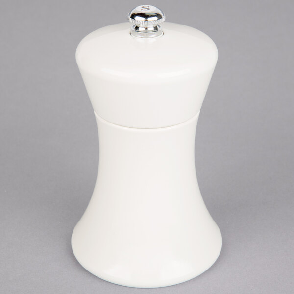 A white salt mill with a silver top.