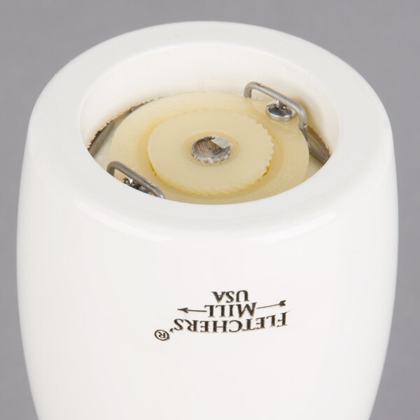 A white Fletchers' Mill Marsala pepper mill on a white table.