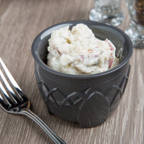 A bowl of mashed potatoes in a Fenwick insulated bowl with a fork on a table.