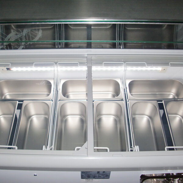 A white Excellence gelato dipping cabinet with seven metal containers of gelato inside.