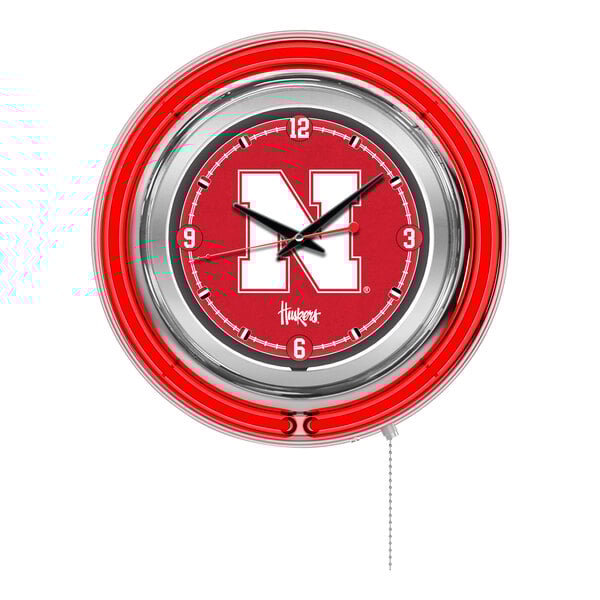 A round wall clock with a red neon border and the University of Nebraska logo in the center.