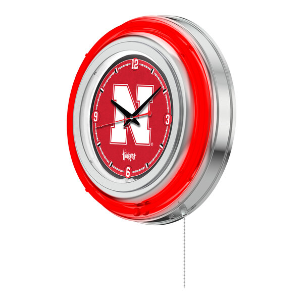 A round wall clock with a red neon border and the University of Nebraska logo in the center.
