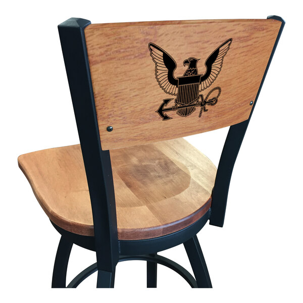 A black steel Holland Bar Stool bar height swivel chair with maple back and seat and a United States Navy logo laser engraved on the back.