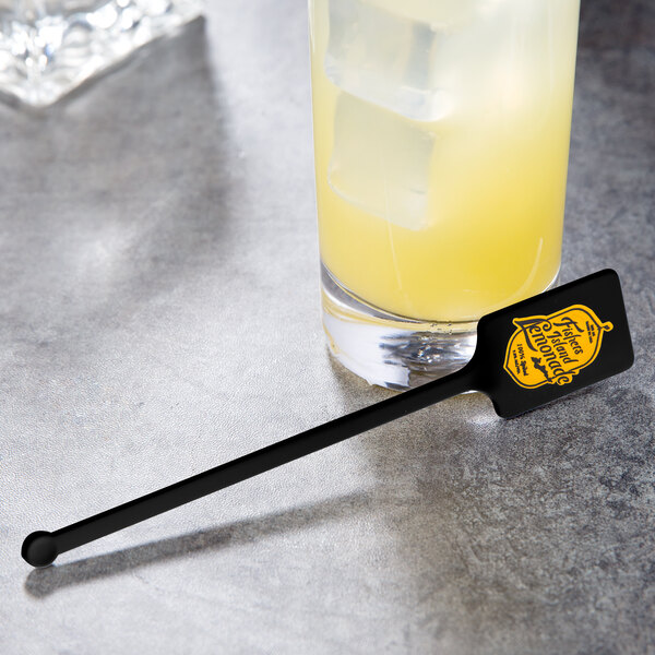 A black rectangular stirrer in a drink with ice cubes.