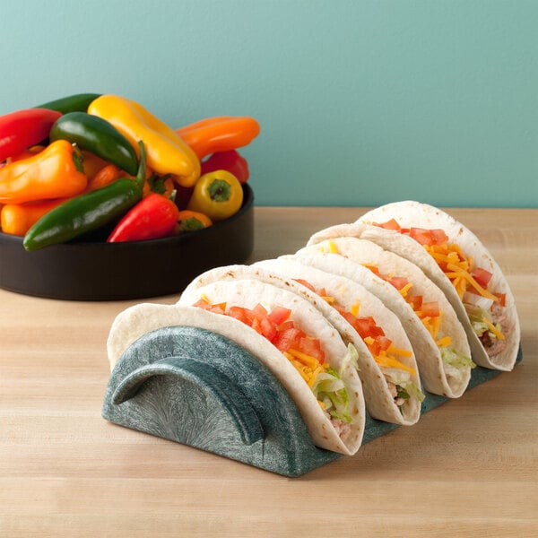 A row of tacos on a HS Inc. jalapeno shell taco server with cheese and vegetables.