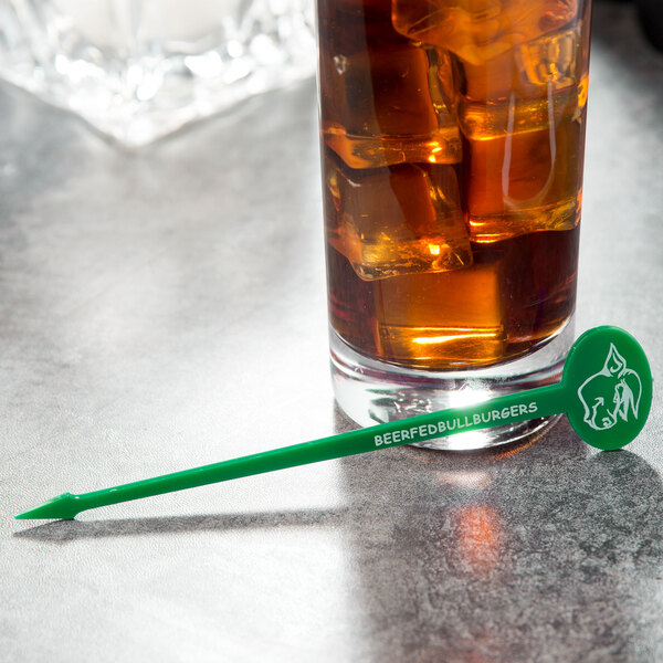 a glass of liquid with ice and a green stick