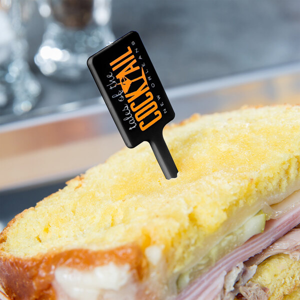A sandwich with a black rectangular pick in it.