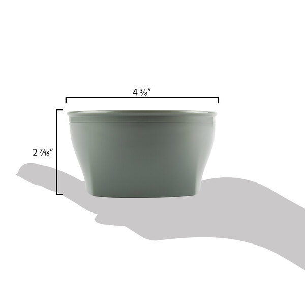 A hand uses a measuring cup to scoop from a white Cambro insulated plastic bowl.