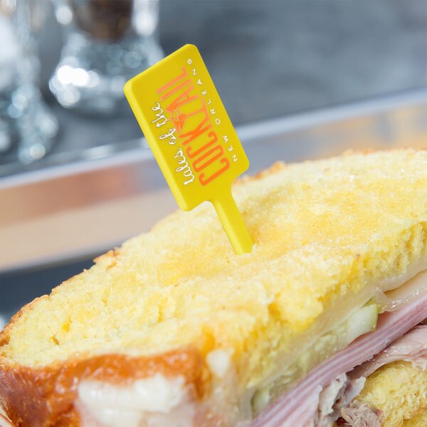 A sandwich with a yellow plastic pick in it.