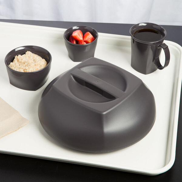 A black plastic tray with a bowl of oatmeal and strawberries in a Cambro Smoked Metal insulated bowl.