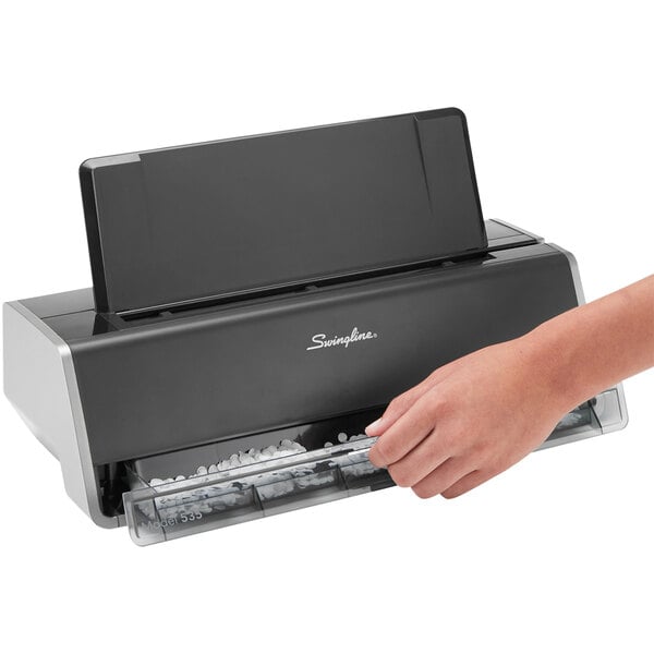 A hand pressing a paper into a black Swingline 3 hole punch.