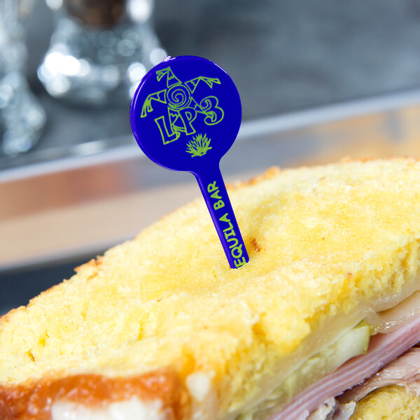 A sandwich with a blue plastic disc pick in the middle.