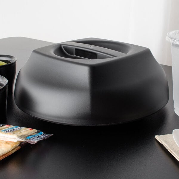 A black Cambro plate cover with food on a table.