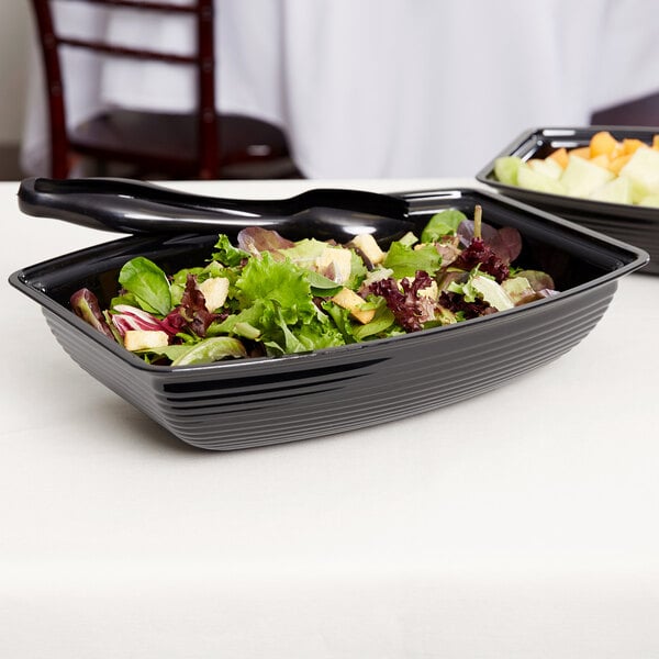 A bowl of salad in a black Cambro rectangular ribbed bowl.