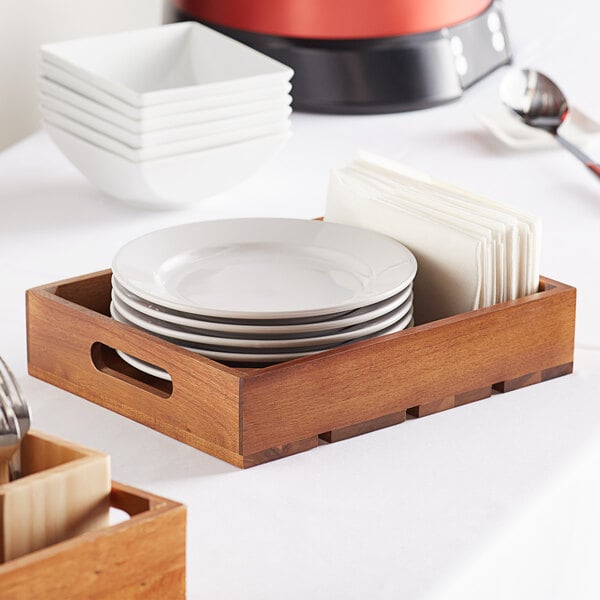 A Tablecraft acacia wood crate with plates and napkins on it.